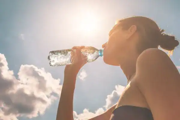 Hydration: The Secret Ingredient for a Toned Stomach and Enhanced Fitness 3 Image of woman drinking water to hydrate Woking after run.