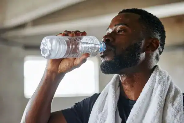 Hydration: The Secret Ingredient for a Toned Stomach and Enhanced Fitness 1 Image of man drinking water to improve hydration Woking after work out.